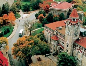 Photo shows a close aerial view of the University of Kansas, Lawrence, campus with limestone buildings and red tile roofs.